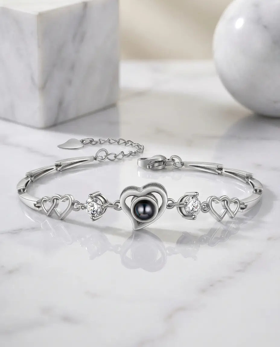 Armbånd af sammenflettede hjerteled med et hjerte kantet af små krystaller og en sten med billede.