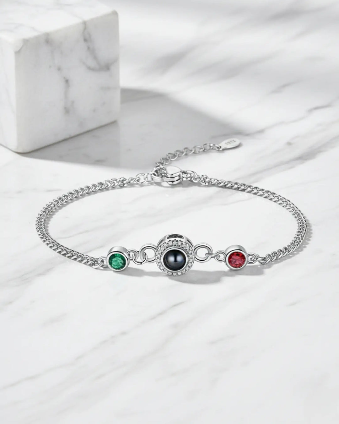 Armbånd med en midterperle, der rummer et personligt billede indeni, flankeret af to farvede fødselssten.