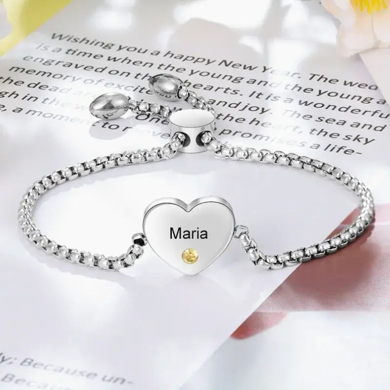 Armbånd i rustfrit stål med poleret hjertecharm, farvede fødselsstensperler og et indgraveret navn.