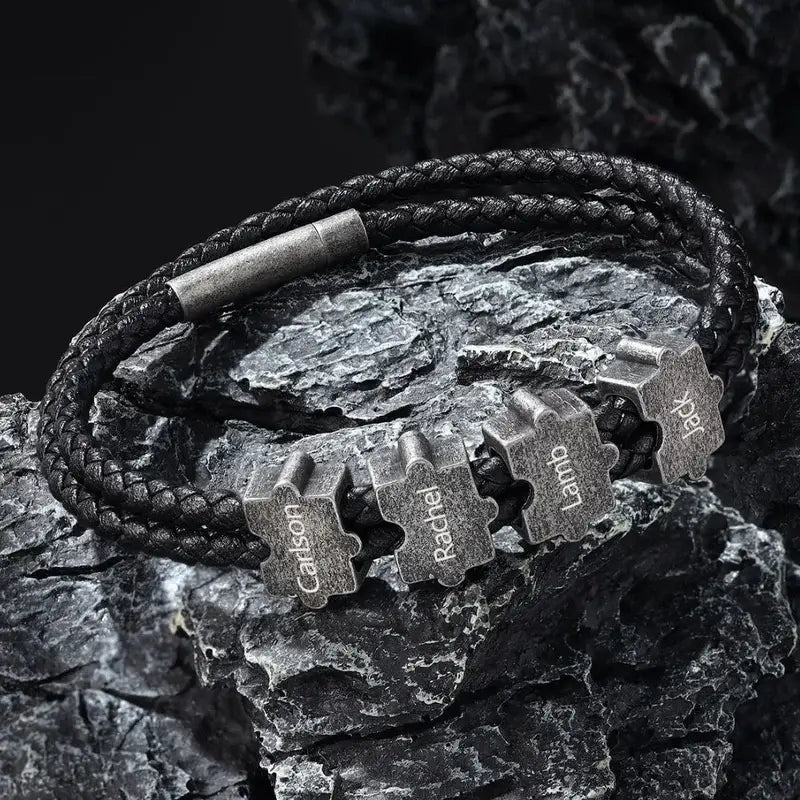 Sort læderarmbånd til mænd med børstede puslespilsperler i rustfrit stål, der griber ind i hinanden.