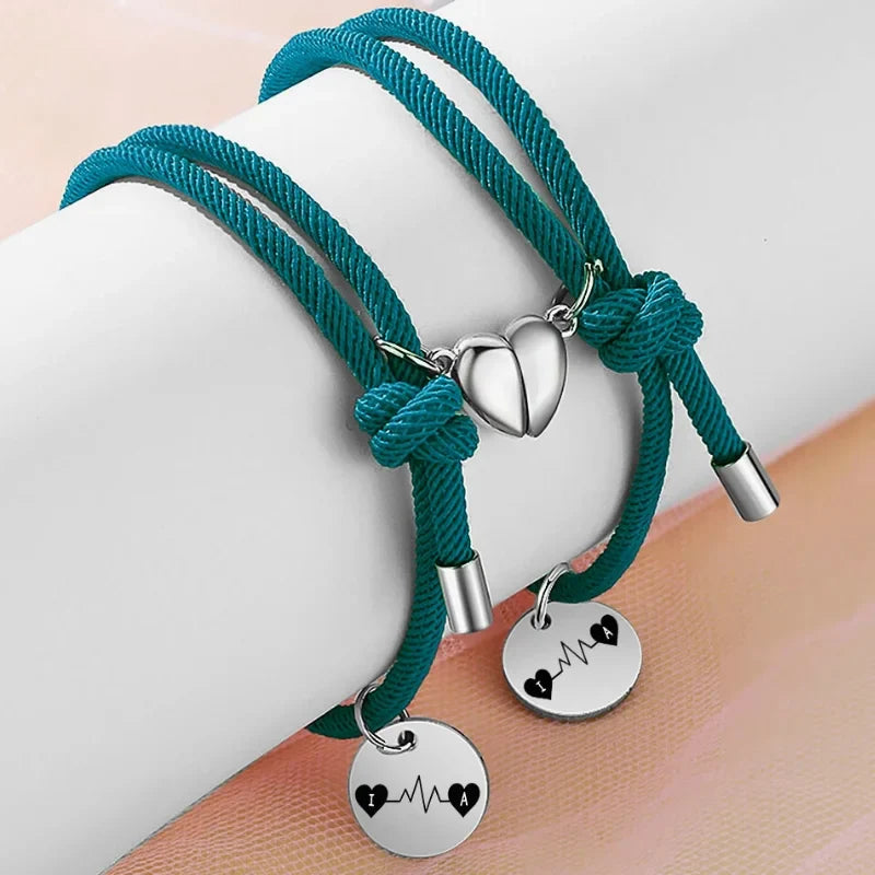 To marineblå armbånd i rustfrit stål med hjertecharms, der klikker sammen med magnet, og initialer.