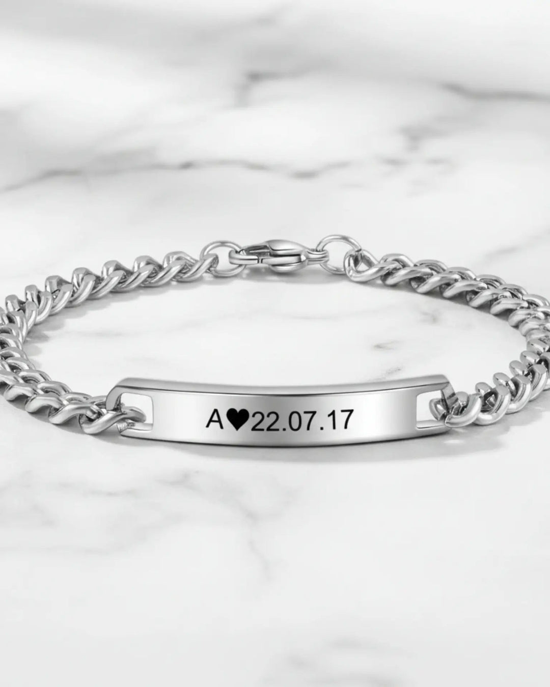 To matchende armbånd med polerede plader med indgraveret initial og dato på kraftige panserkæder.