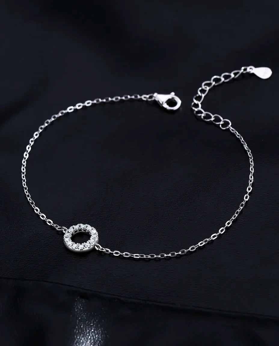 Sølvarmbånd med en åben cirkel fattet med tretten små moissanite-sten hele vejen rundt i 925 sterling sølv.
