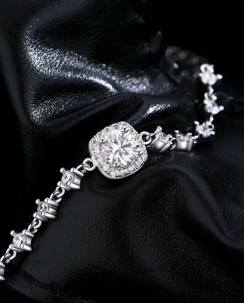 Sølvarmbånd med pudeslebet moissanite på 6 mm i halofatning og små sten langs kæden i 925 sterling sølv.