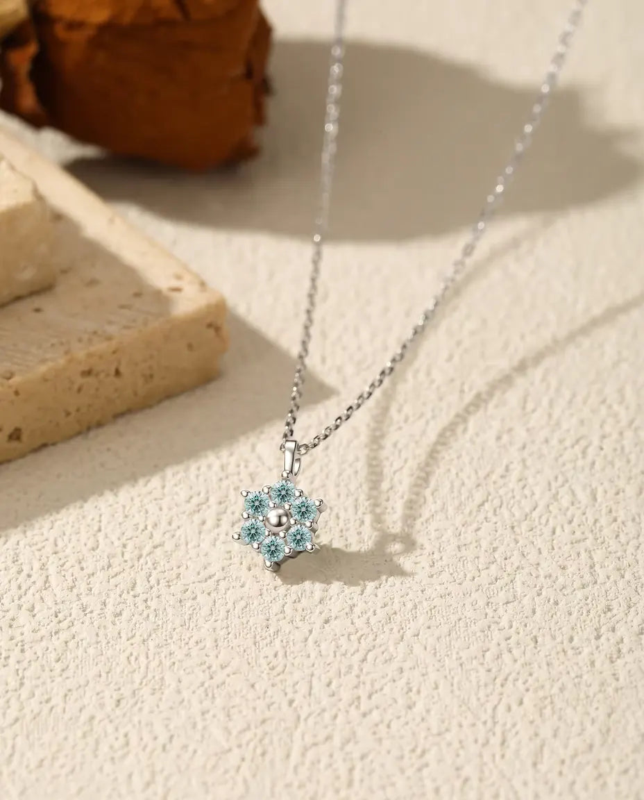 Blomstervedhæng med seks aquablå moissanite omkring en poleret sølvkugle i 925 sterling sølv.