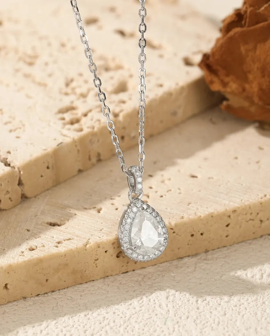 Stor dråbeformet moissanite med en halo af små sten hele vejen rundt i rhodineret 925 sterling sølv.