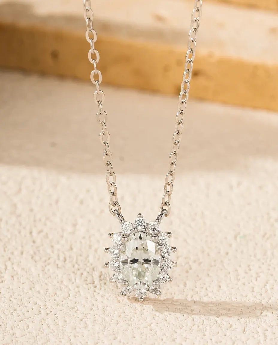 Oval moissanite omkranset af en pavésat halo på et vedhæng på 10 mm i rhodineret 925 sterling sølv.