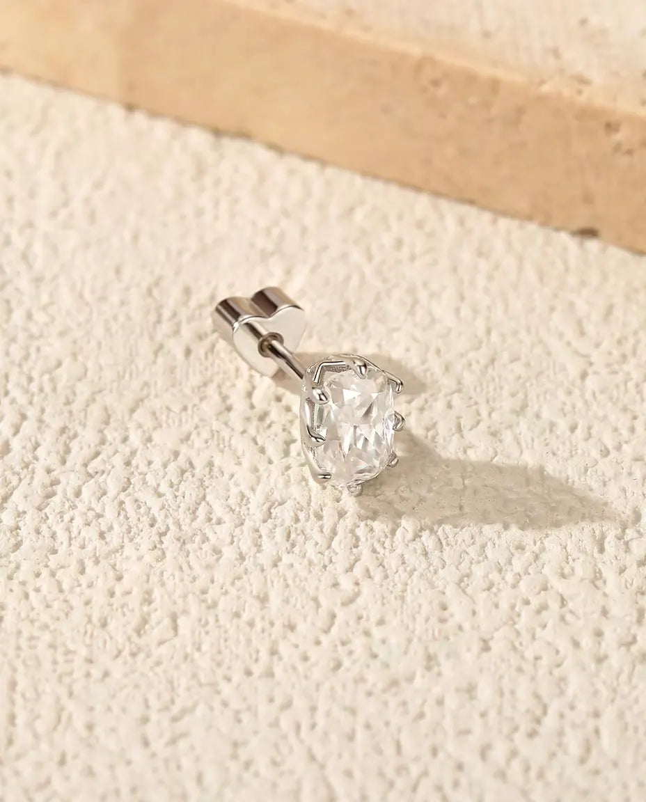 En ørestik i 925 sterling sølv med en radiantsleben moissanite i seks kløer, lagt på råhvid puds ved travertin.