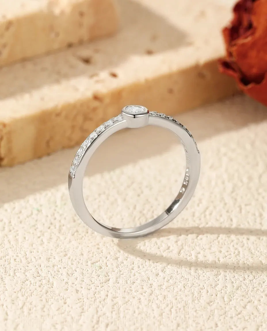 Tynd sølvring med lille rund moissanite i lukket fatning og pavéskuldre i zirkonia, 925 sterling sølv.