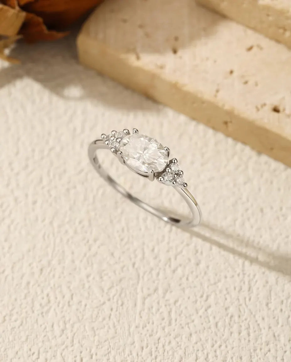 Sølvring med oval moissanite sat på tværs af fingeren og tre små zirkonia på hver skulder i 925 sterling sølv.