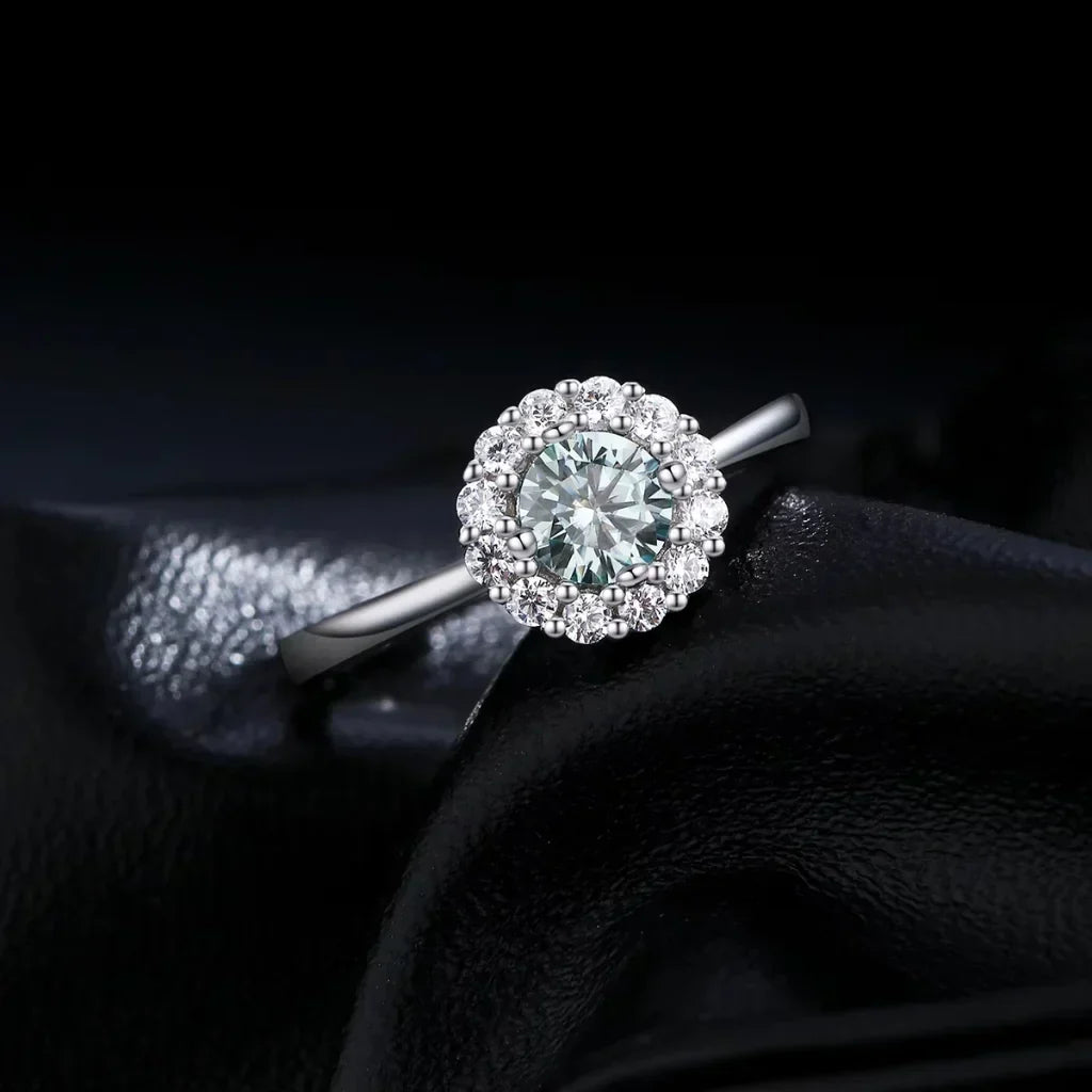 Sølvring med petrolgrøn moissanite omkranset af en halo af små klare sten i 925 sterling sølv.