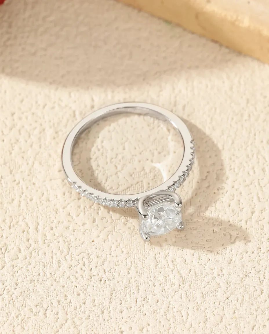 Sølvring med pudeslebet moissanite på 6 mm i fire klør over en smal skinne med pavéfattede zirkoner.