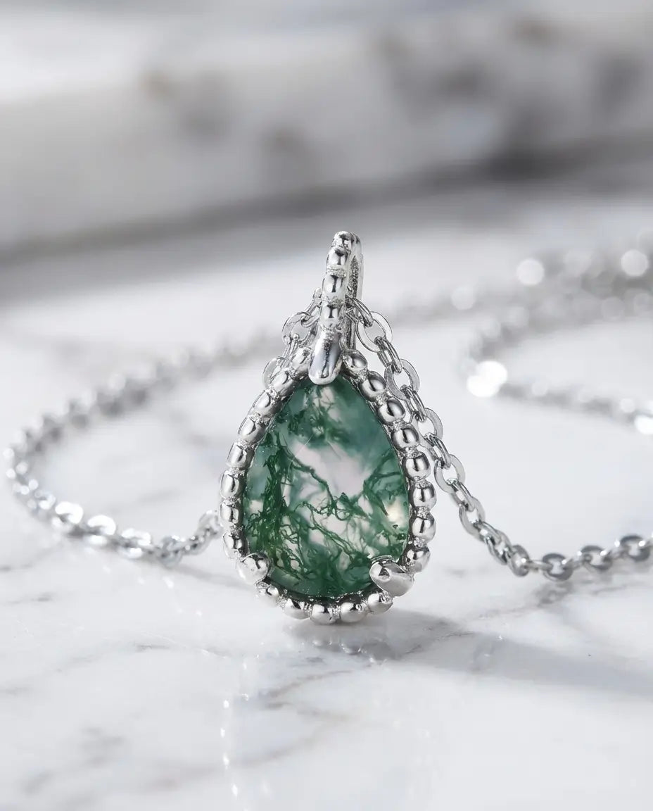 Dråbeslebet grøn moss agate på 6x8 mm i en enkel fatning af sterling sølv på en fin kæde.
