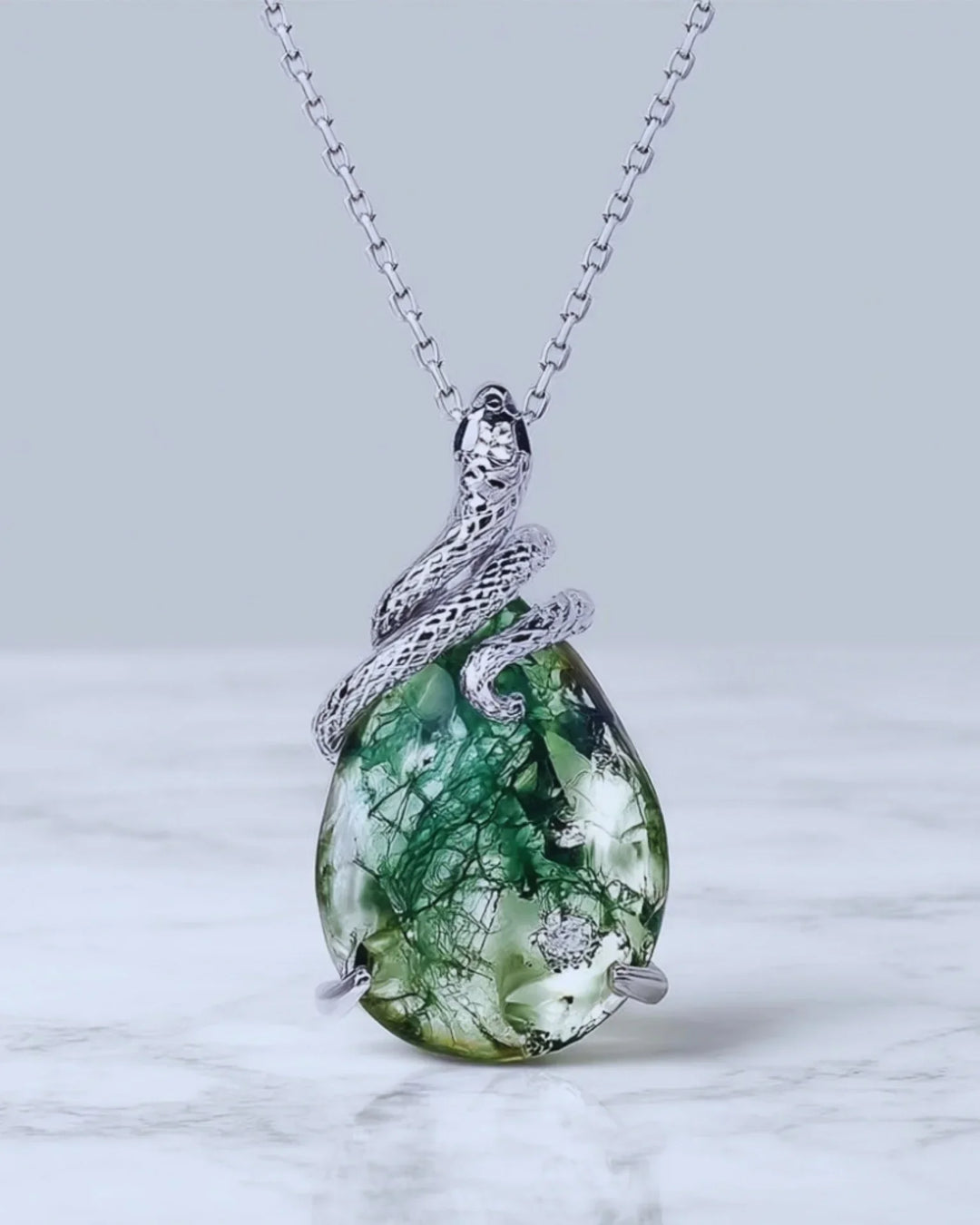 Stor pæreslebet grøn moss agate holdt af en fint ciseleret sølvslange i 925 sterling sølv.