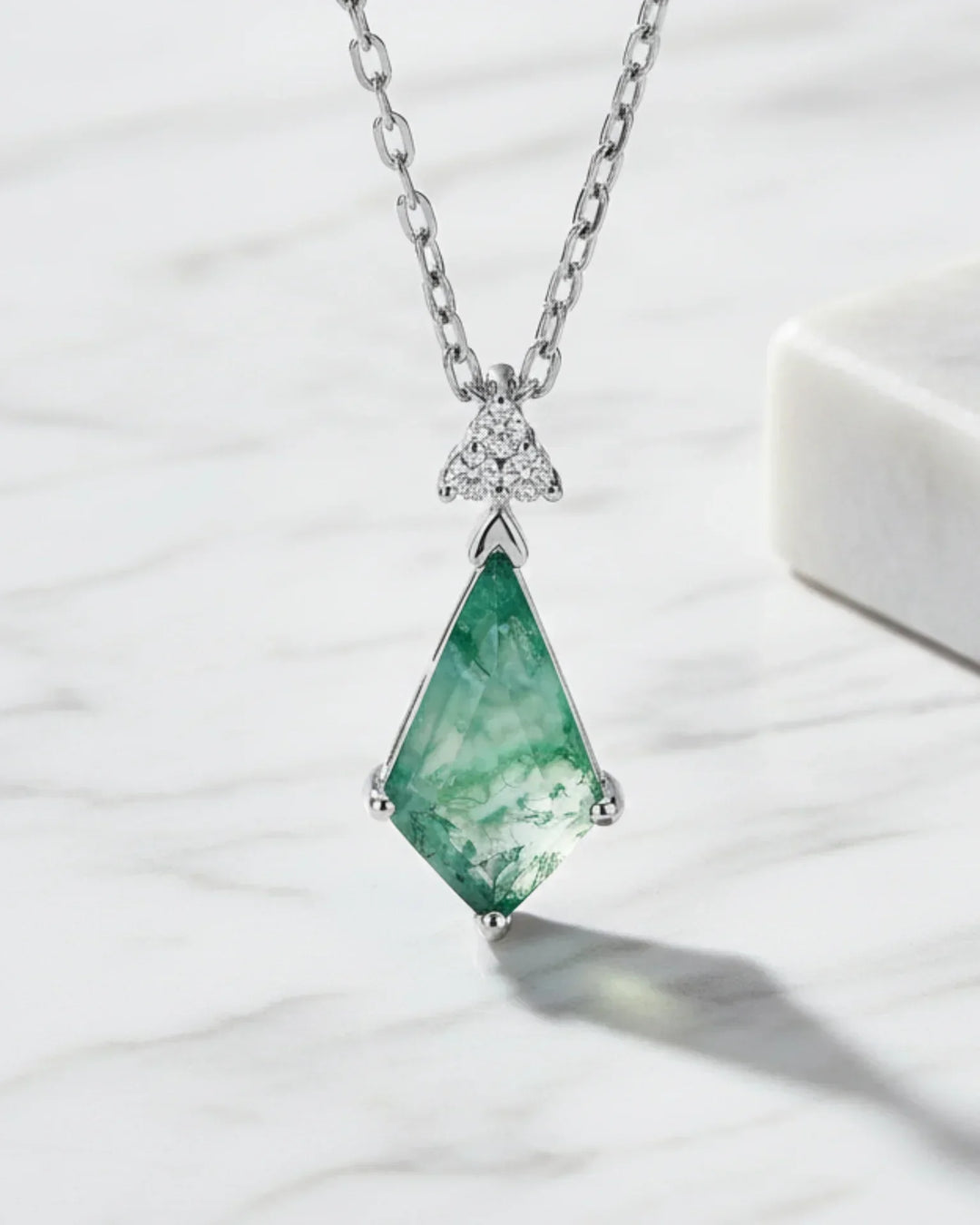 Kiteslebet grøn moss agate omgivet af en kant af zirkoner i et vedhæng af 925 sterling sølv.