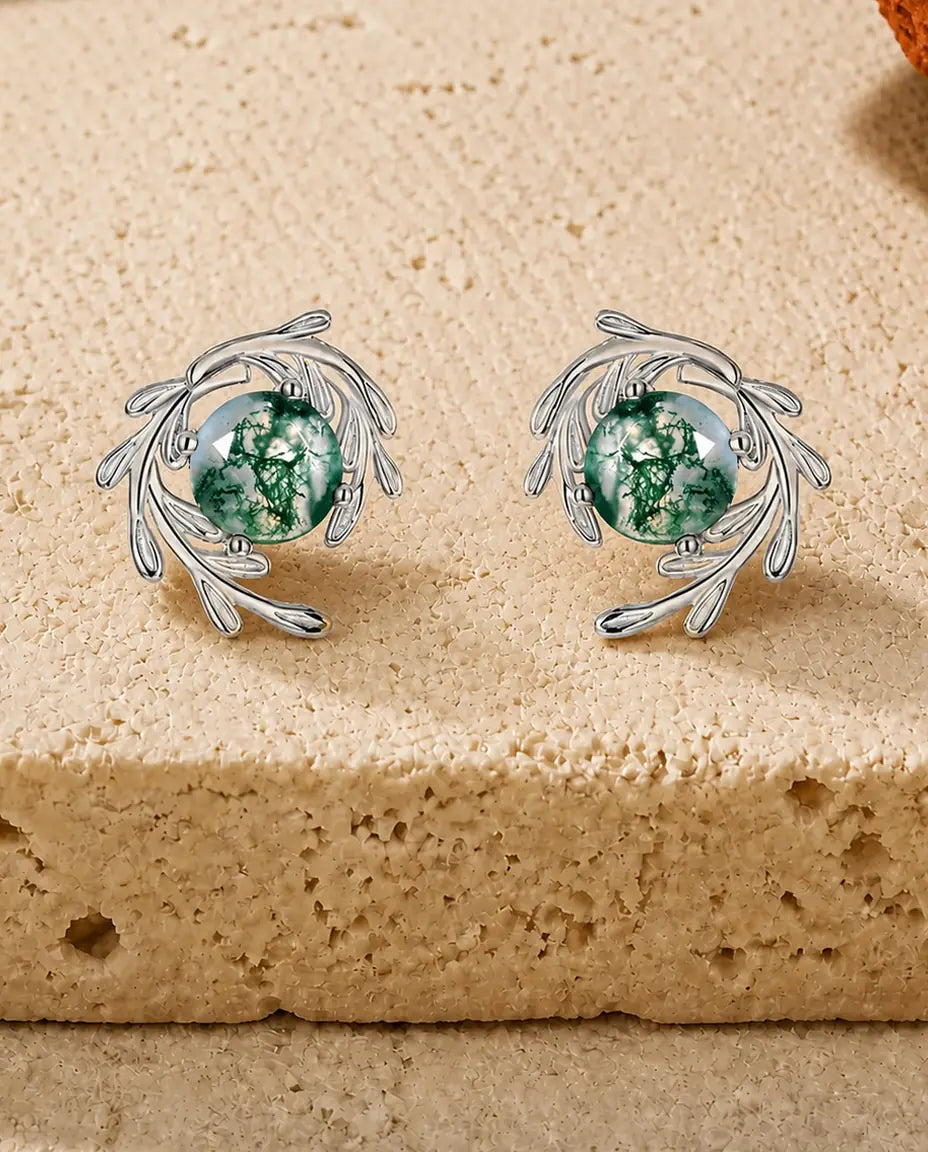 Ørestikker med rund grøn Moss Agate midt i en hvirvel af polerede sølvranker med oprullede spidser.