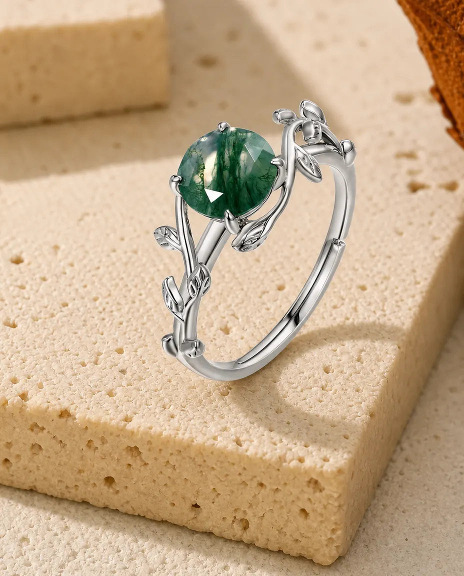 Tynd sølvring med små blade langs skinnen og en rund rosenslebet grøn moss agate i fire klør, 925 sølv.