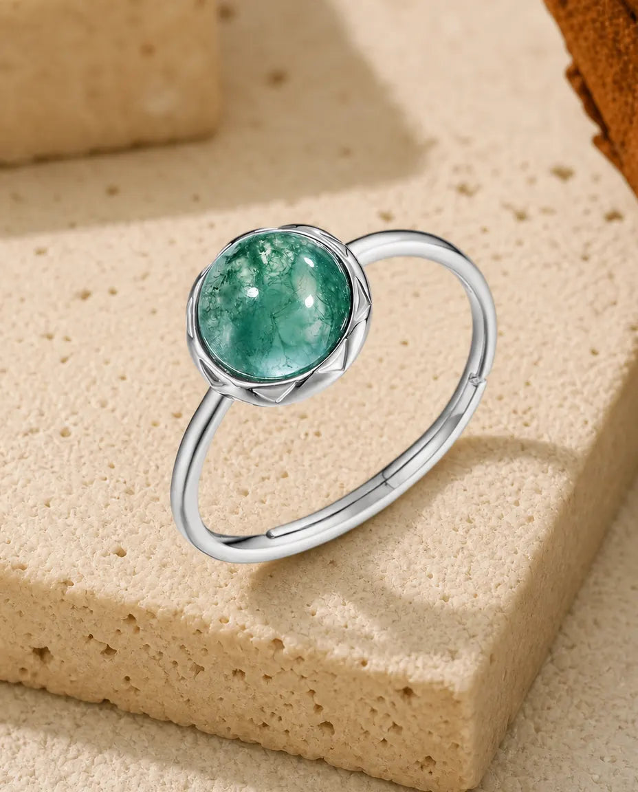 Tynd sølvring med rund grøn moss agate-cabochon i en lukket fatning med kronbladsmønster i 925 sterling sølv.