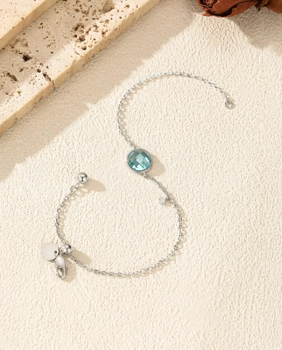 Fin kæde i 925 sterling sølv med en lyseblå ternslebet zirkonia på 8 mm og en lille klar sten længere nede.