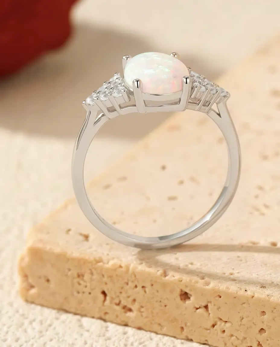 Sølvring med oval hvid opal i fire klør og små klare sten i pavé på begge skuldre, 925 sterling sølv.