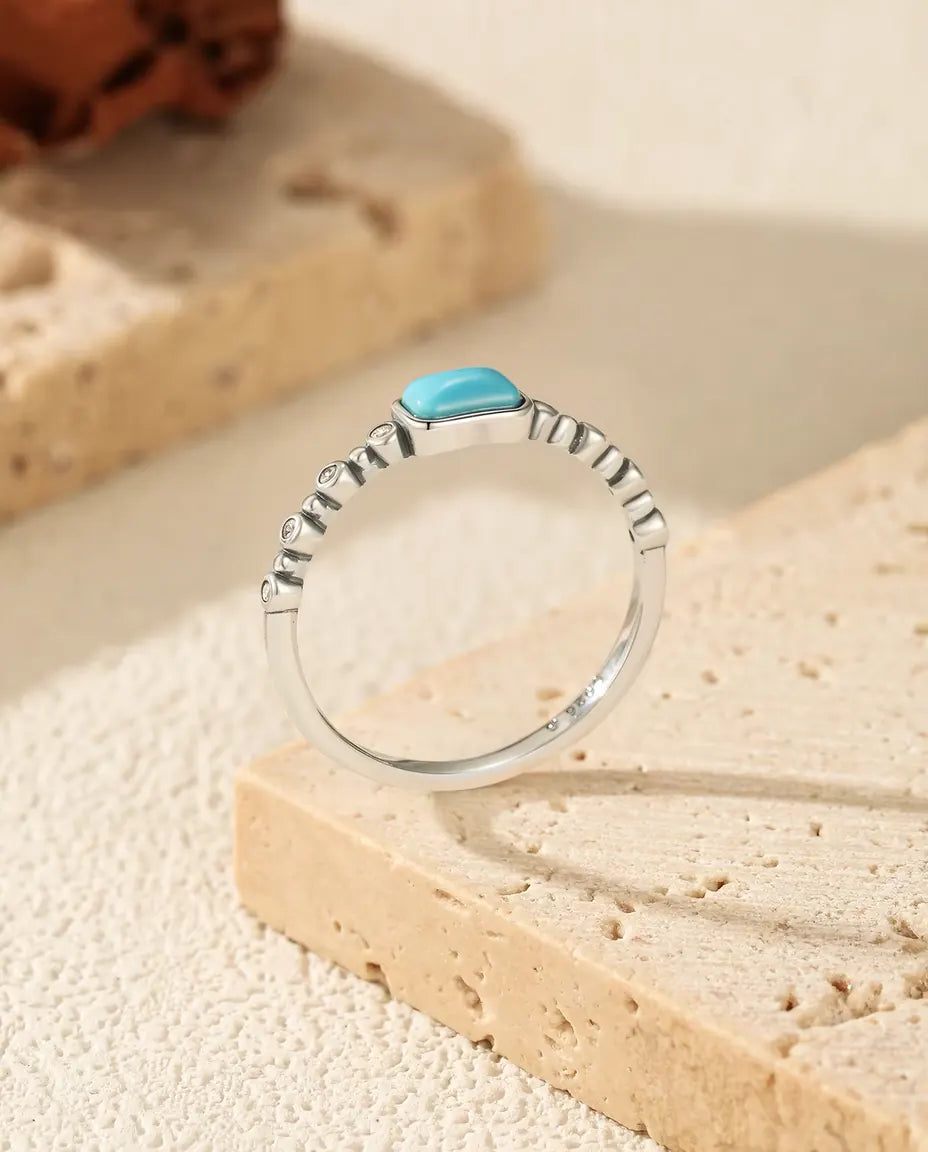 Smal sølvring med rektangulær turkis cabochon i lukket fatning og små zirkonia i 925 sterling sølv.