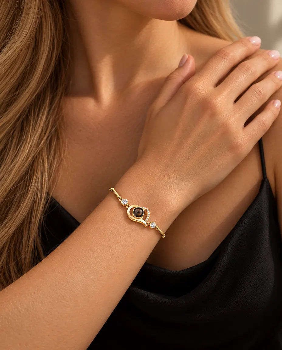 Nærbillede af det guldfarvede armbånd med åbent hjerte og zirkonia om et håndled ved kravebenet