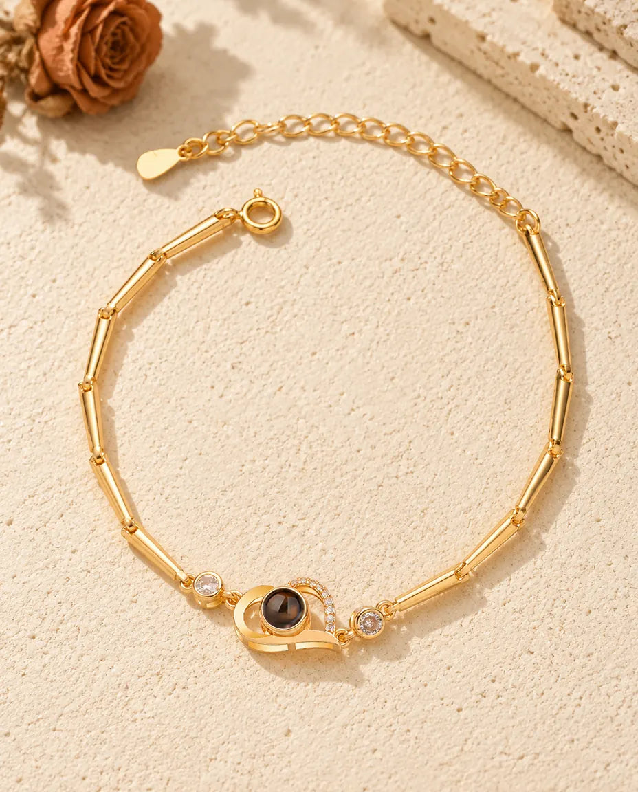 Det guldfarvede armbånd med åbent hjerte og billede indeni set oppefra