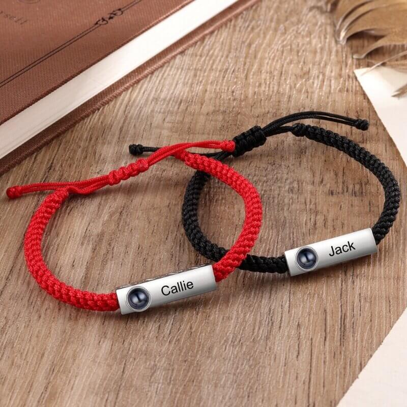 Rødt og sort armbånd i kobber med en poleret barre, der gemmer et lille billede bag en linse.