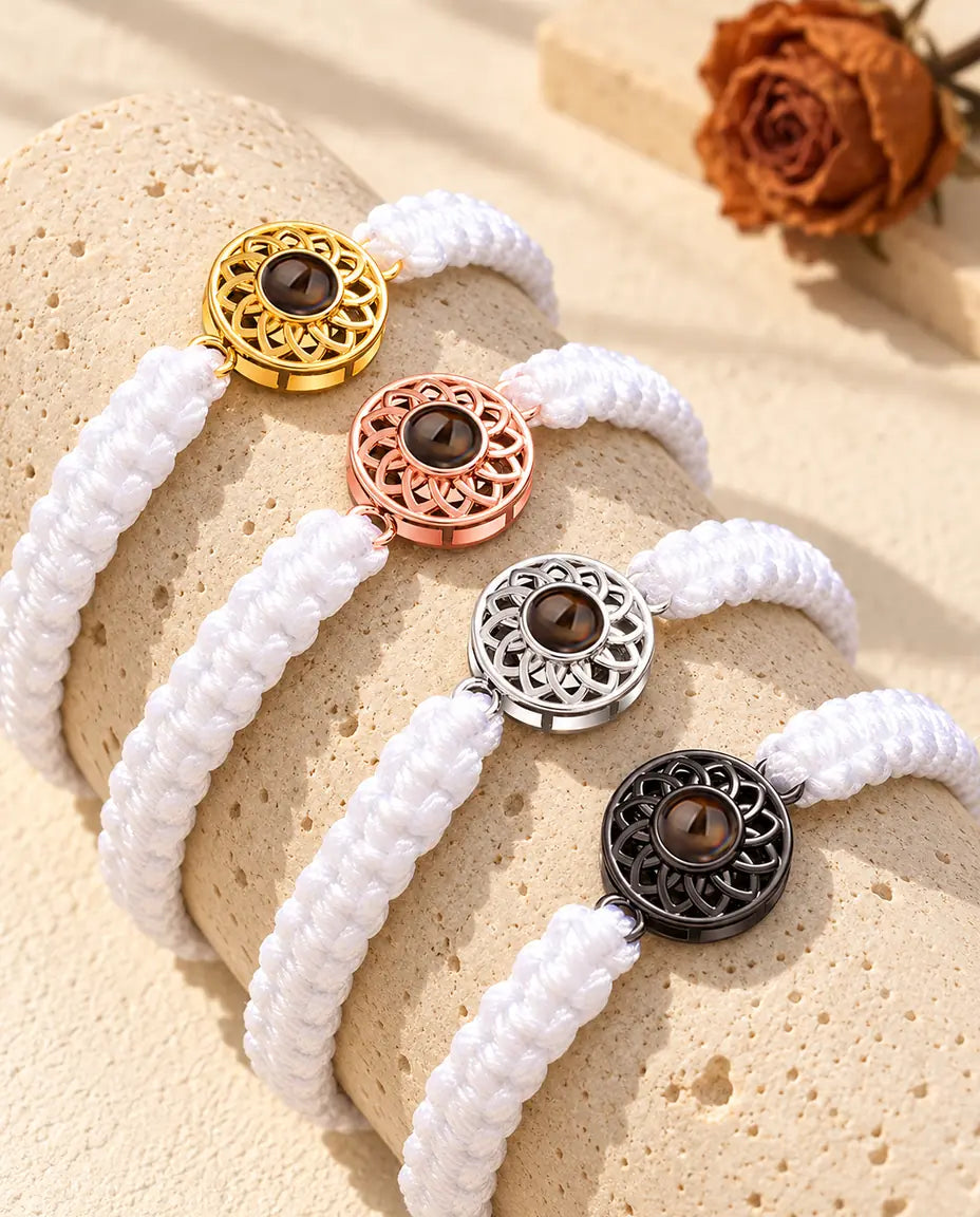 Fire hvide flettede armbånd med runde charms i guldfarvet, rosaguldfarvet, sølvfarvet og sort på travertin