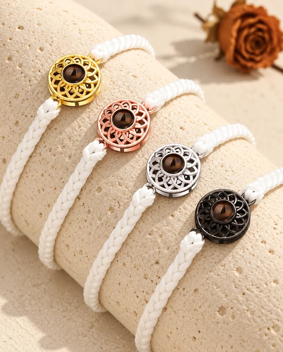 Fire tynde hvide flettede armbånd med runde charms i guldfarvet, rosaguldfarvet, sølvfarvet og sort