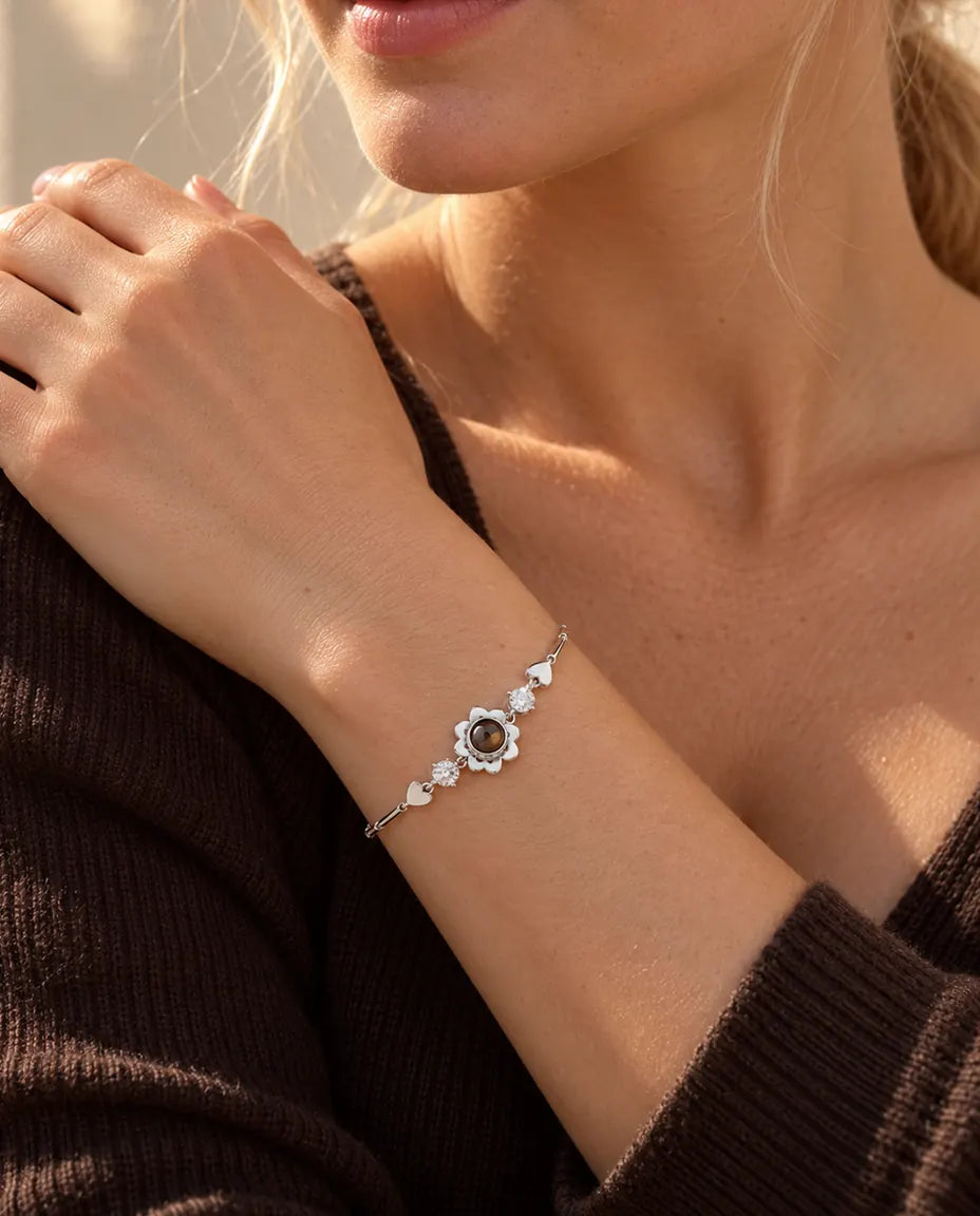 Kvinde med hånden på skulderen bærer det sølvfarvede armbånd med firkløver og billede indeni