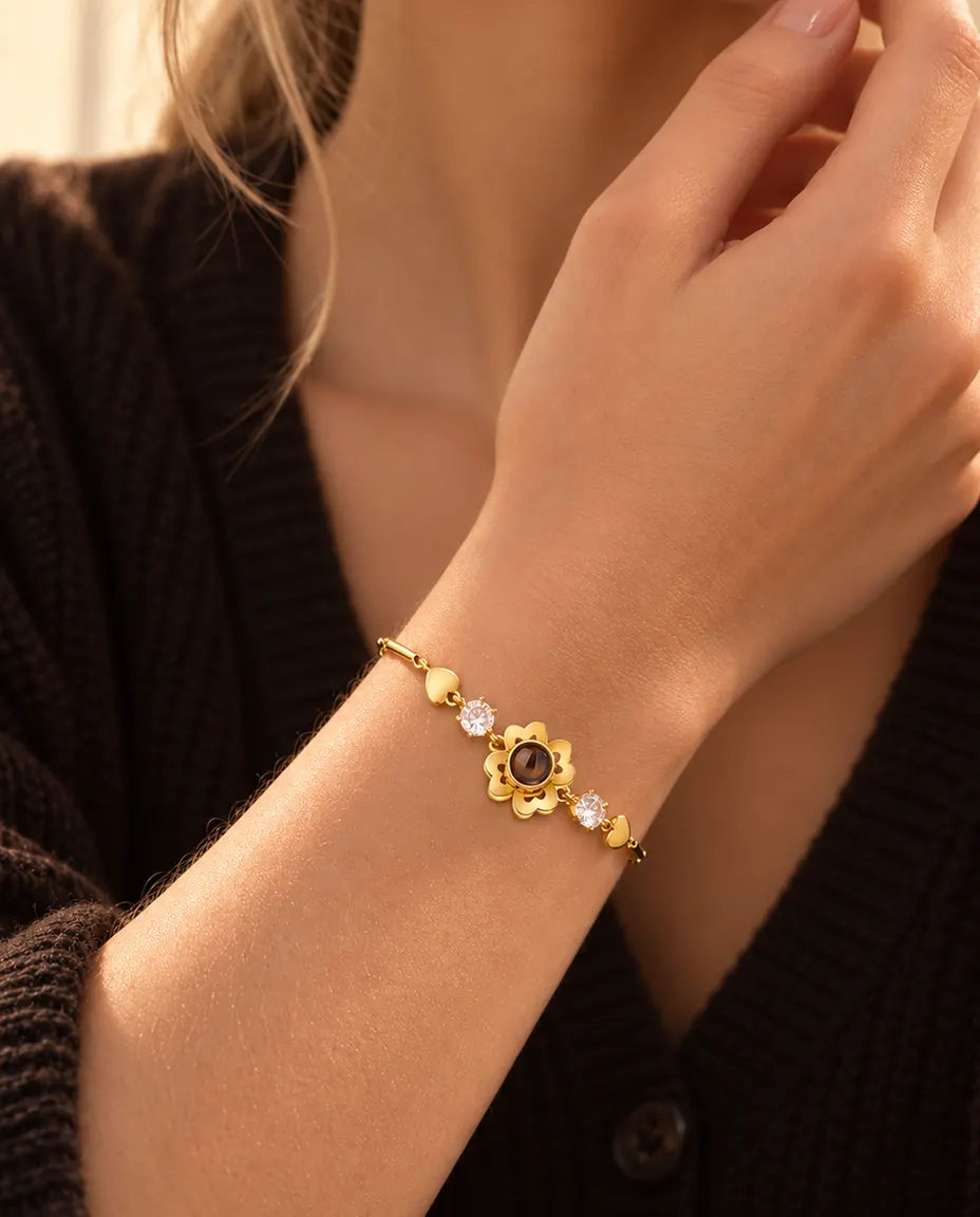 Nærbillede af det guldfarvede armbånd med firkløver og små hjerter om et håndled tæt ved kæben