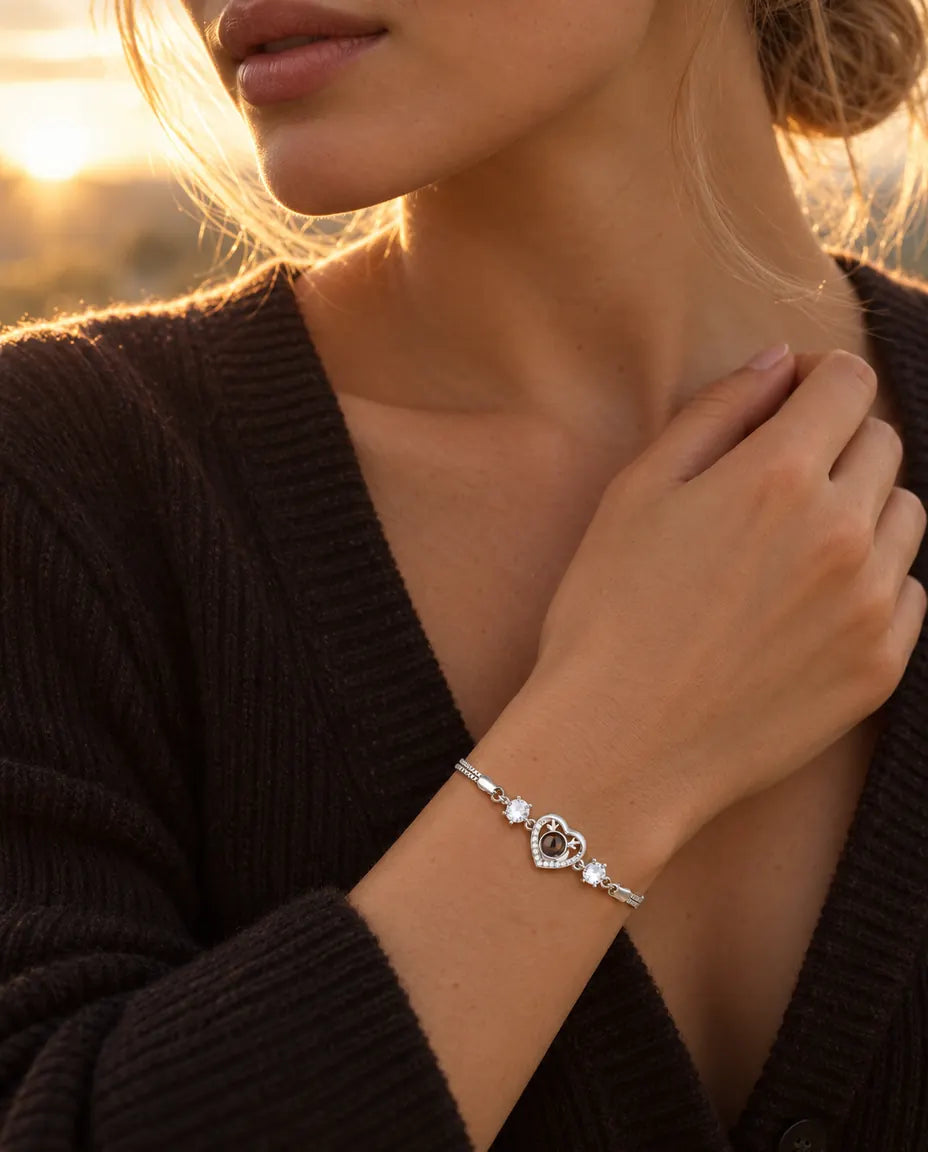 Kvinde rører ved halsudskæringen på sin mørke strik og bærer det sølvfarvede armbånd med gevirhjerte