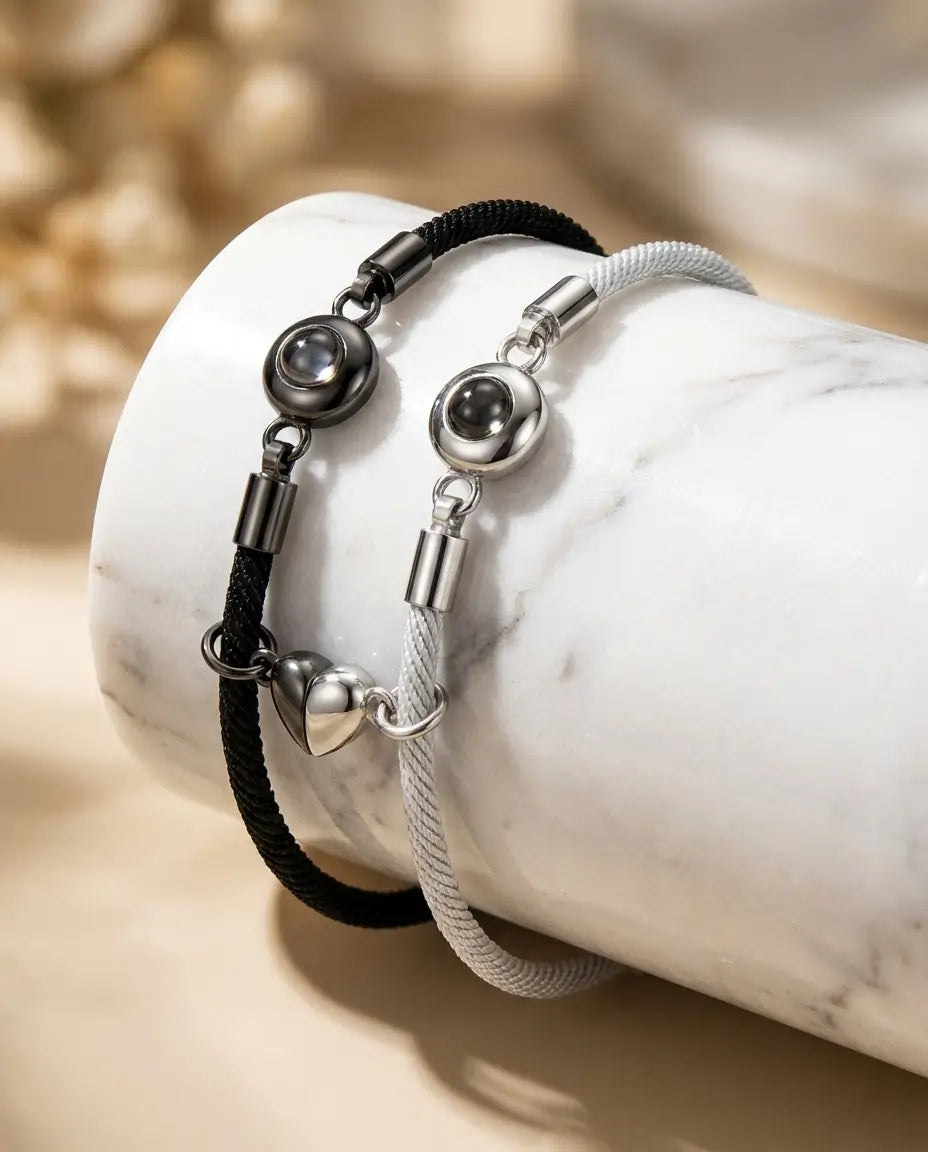 To flettede armbånd med rhodinerede halve hjerter, der samles med magnet og gemmer et billede indeni.