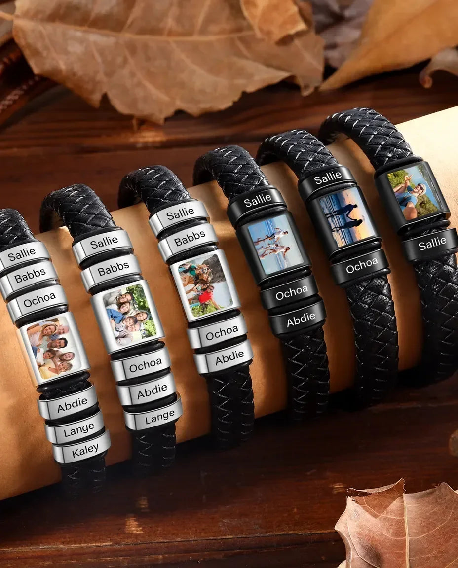 Flettet sort læderarmbånd med en rund fotoperle under glas og flere polerede navneperler i rustfrit stål.