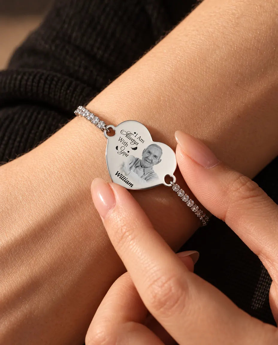 Fingerspidser holder det indgraverede billedhjerte på det sølvfarvede tennisarmbånd