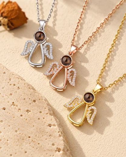 Tre halskæder med engel og billede indeni lagt diagonalt ved en travertinplade