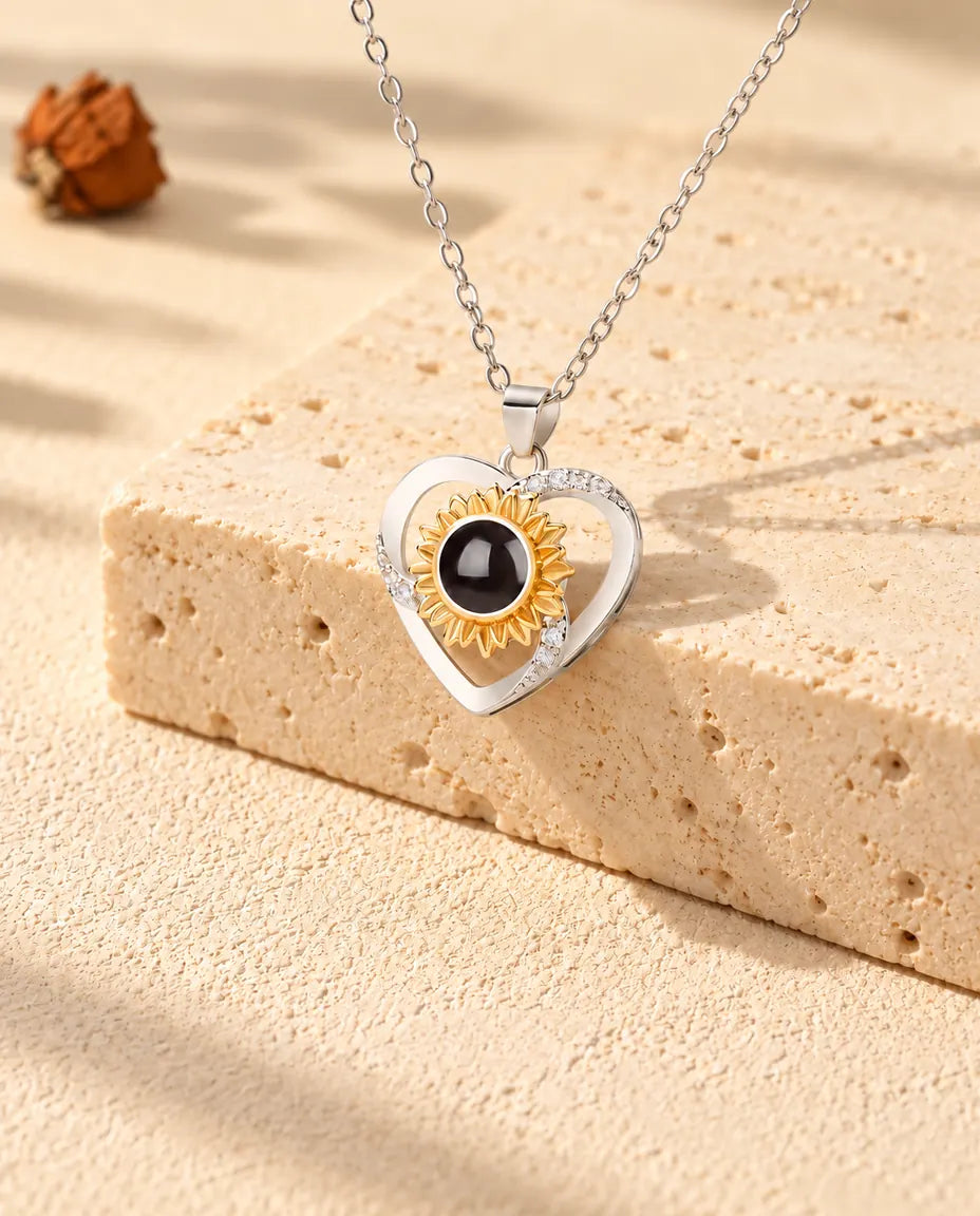 Halskæde med solsikkehjerte og billede indeni lagt over en travertinblok