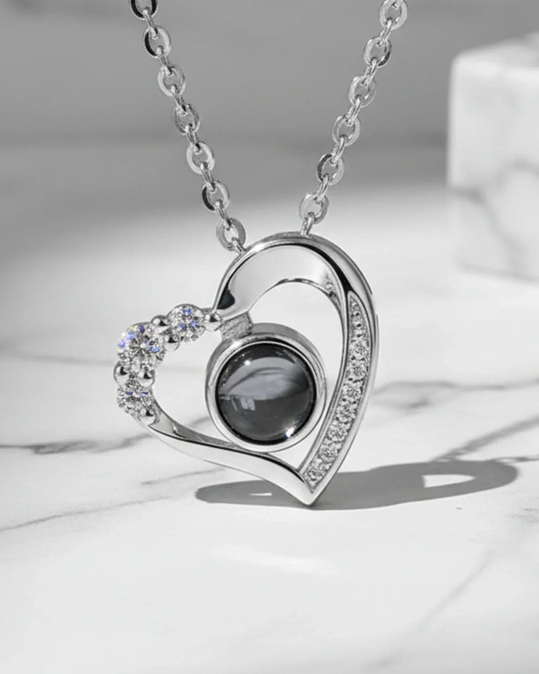 Hjertevedhæng i 925 sterling sølv med zirkoner på den ene side og en midtersten med billede.