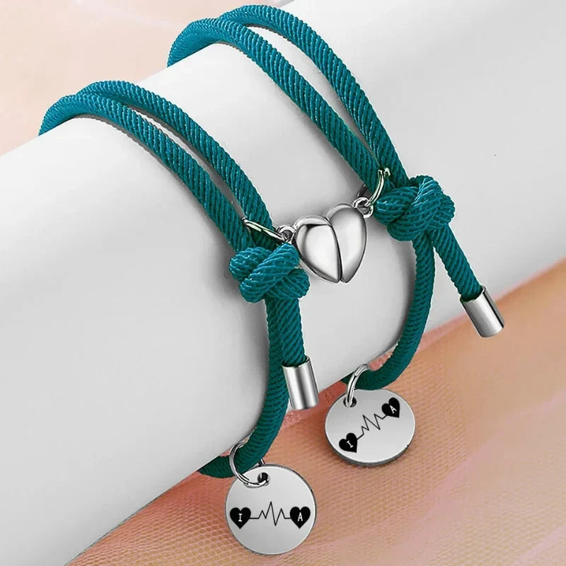 To marineblå armbånd i rustfrit stål med hjertecharms, der klikker sammen med magnet, og initialer.