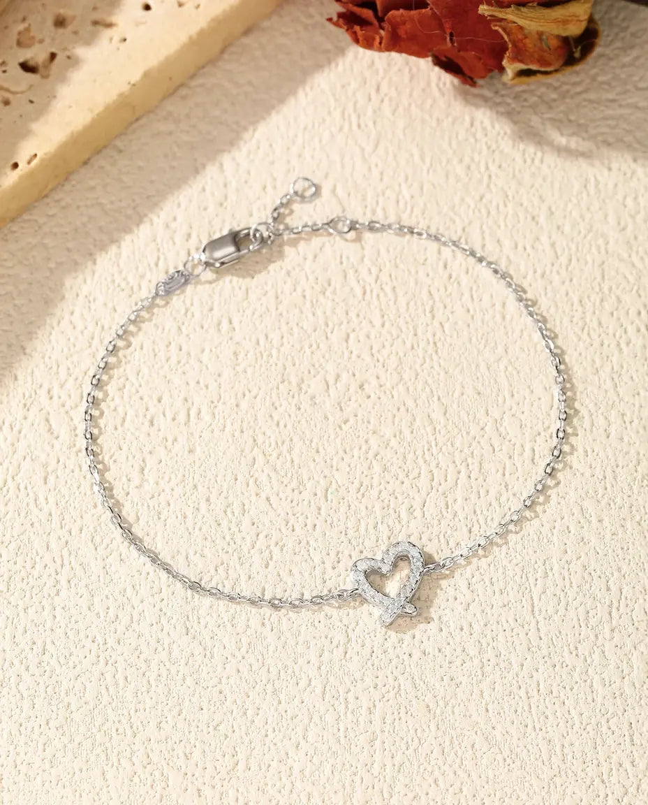 Sølvarmbånd med et åbent hjerte i fri streg og en enkelt klar moissanite i 925 sterling sølv.
