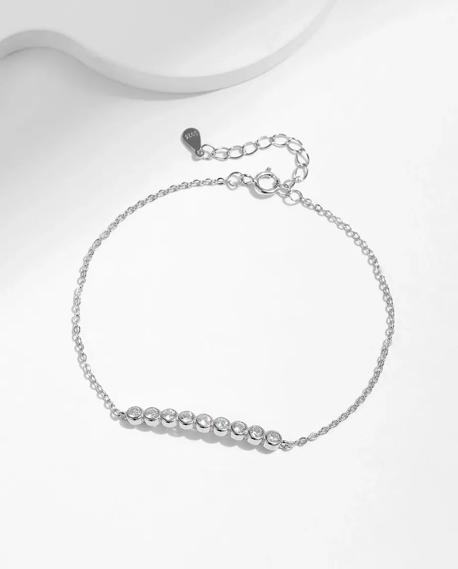 Fin kæde i 925 sterling sølv med ni runde moissanite fordelt i lukkede fatninger langs håndleddet.