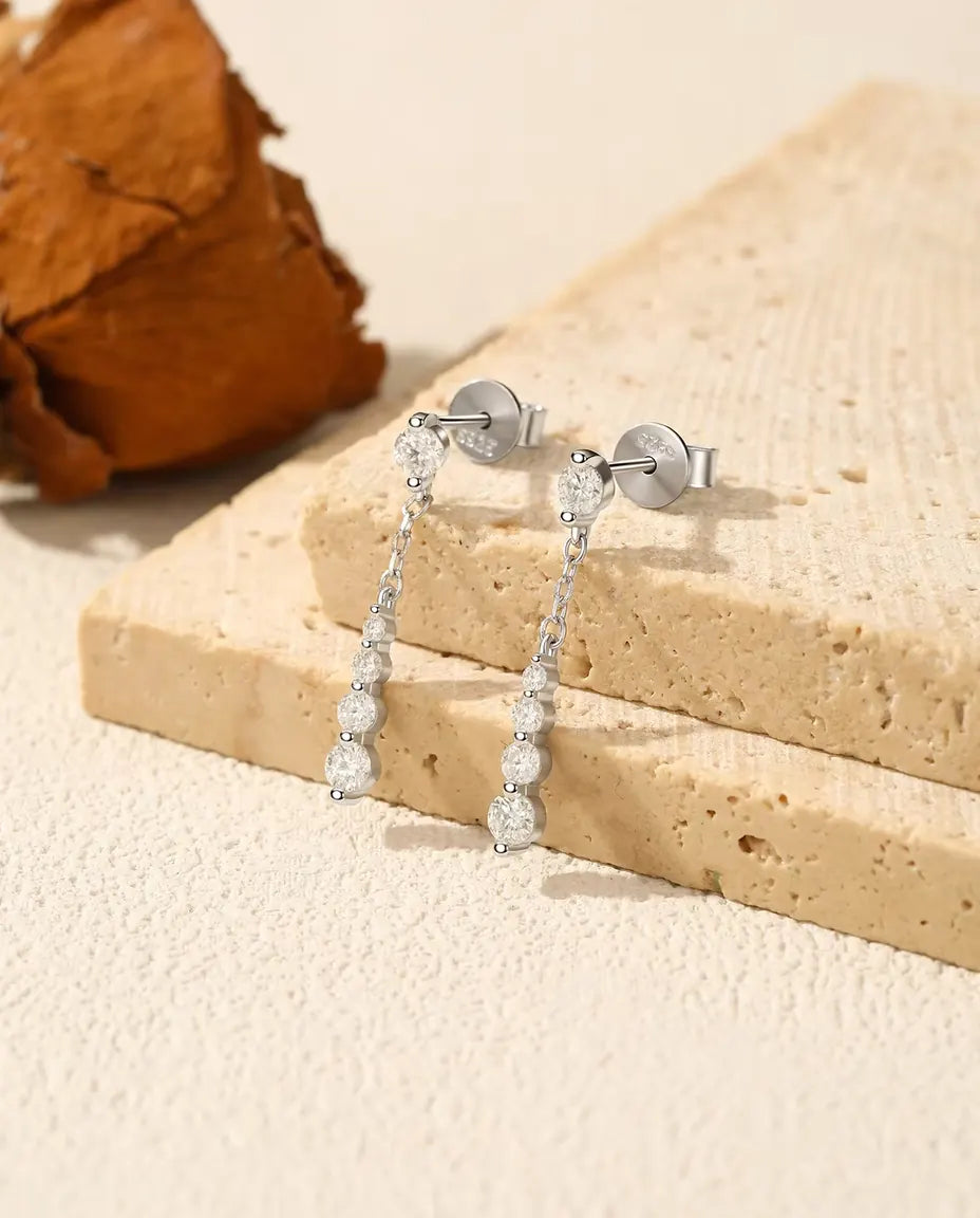 Sølvøreringe med fin kæde og fem moissanite i voksende størrelse ned langs halsen i 925 sterling sølv.