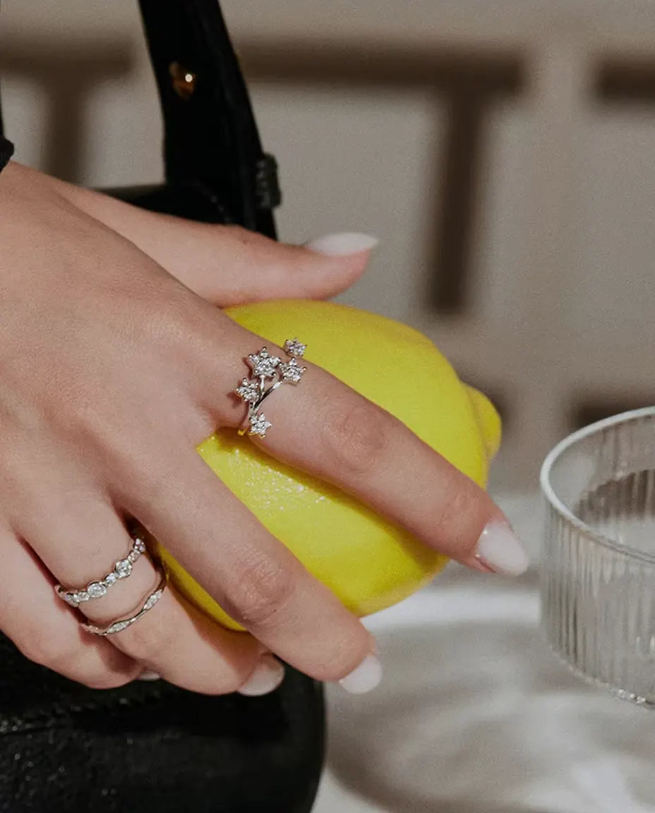 Moissanite Ring i 925 Sølv - båret sammen med andre ringe, hånden holder en citron