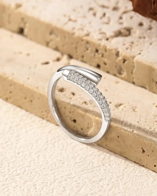 Åben krydset ring i 925 sterling sølv, glat i den ene ende og med to rækker små moissanite-sten i den anden, på travertin.