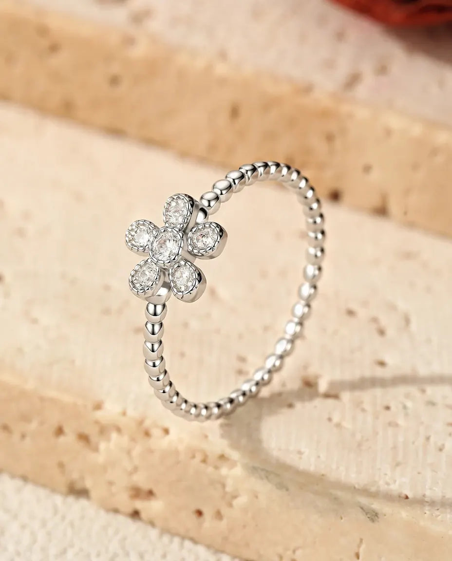 Sølvring med fem små runde moissanitter samlet som en blomst på en perlet skinne i 925 sterling sølv.