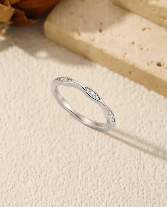 Bølget smal ring i 925 sterling sølv med små marquiseformede fatninger af moissanite-sten, stillet op på råhvid puds.