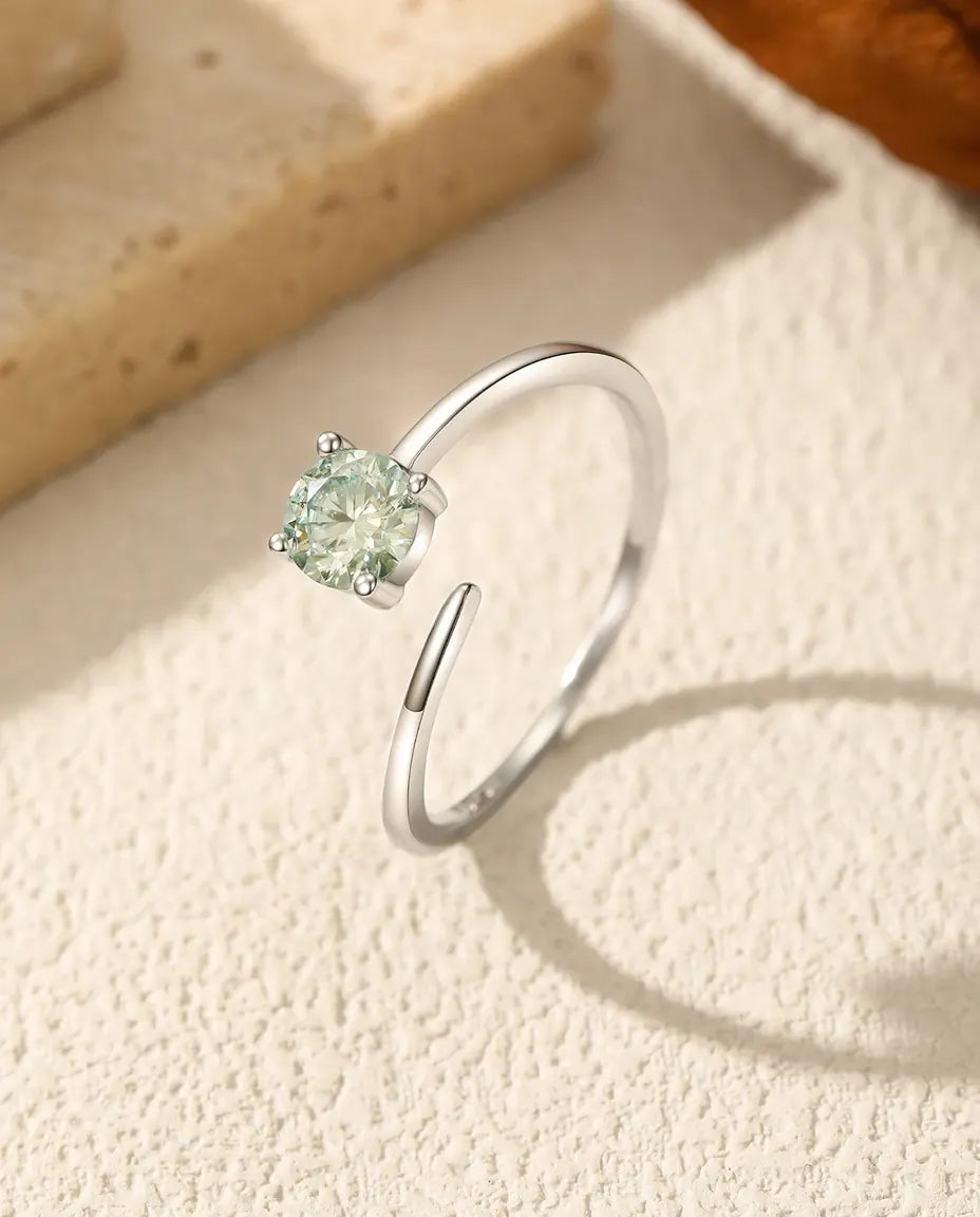 Justerbar sølvring med grøn rund moissanite i fire fine klør på en spinkel, åben skinne i 925 sterling sølv.