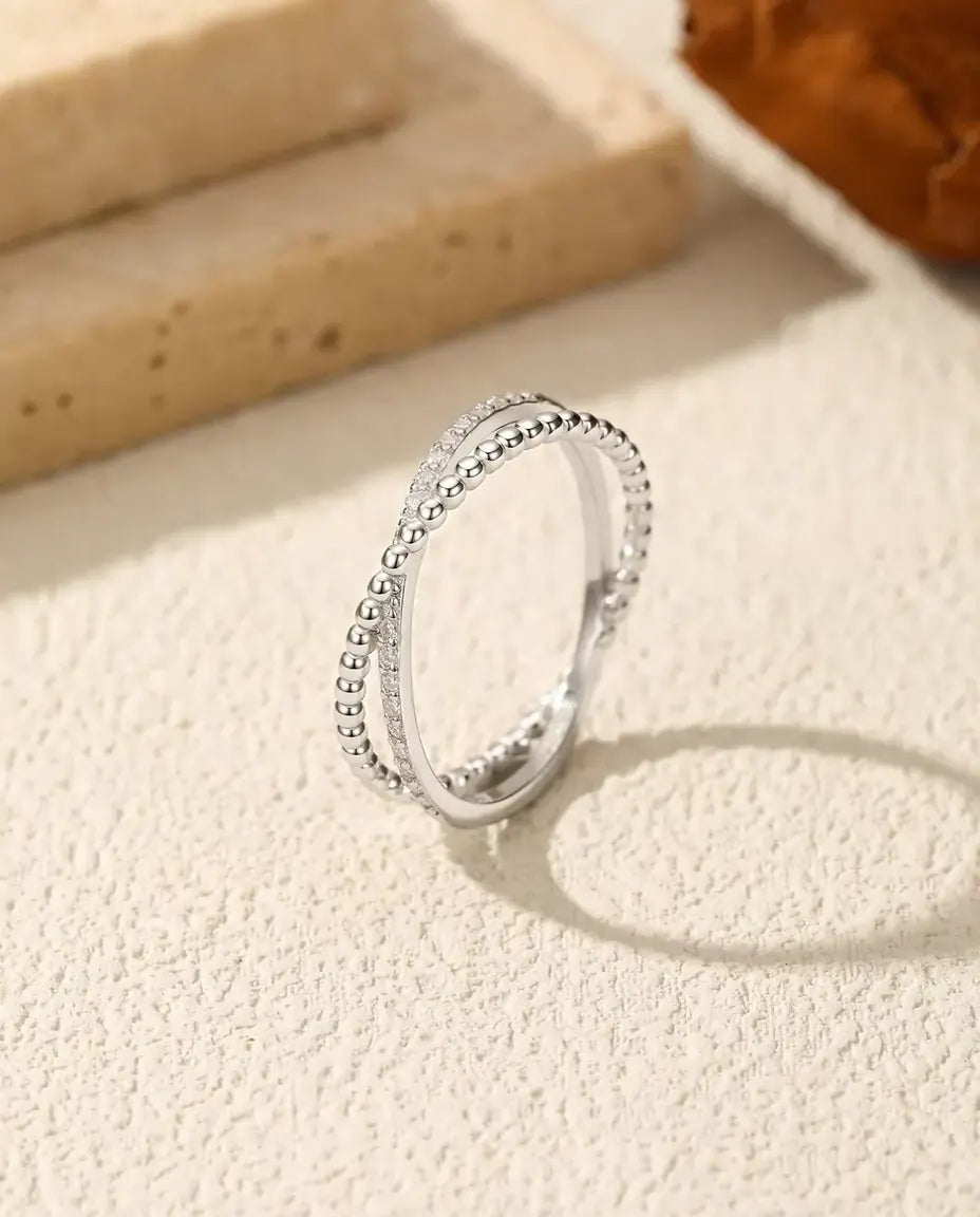 Sølvring hvor en perlet skinne krydser en skinne med atten små moissanite-sten, i 925 sterling sølv.