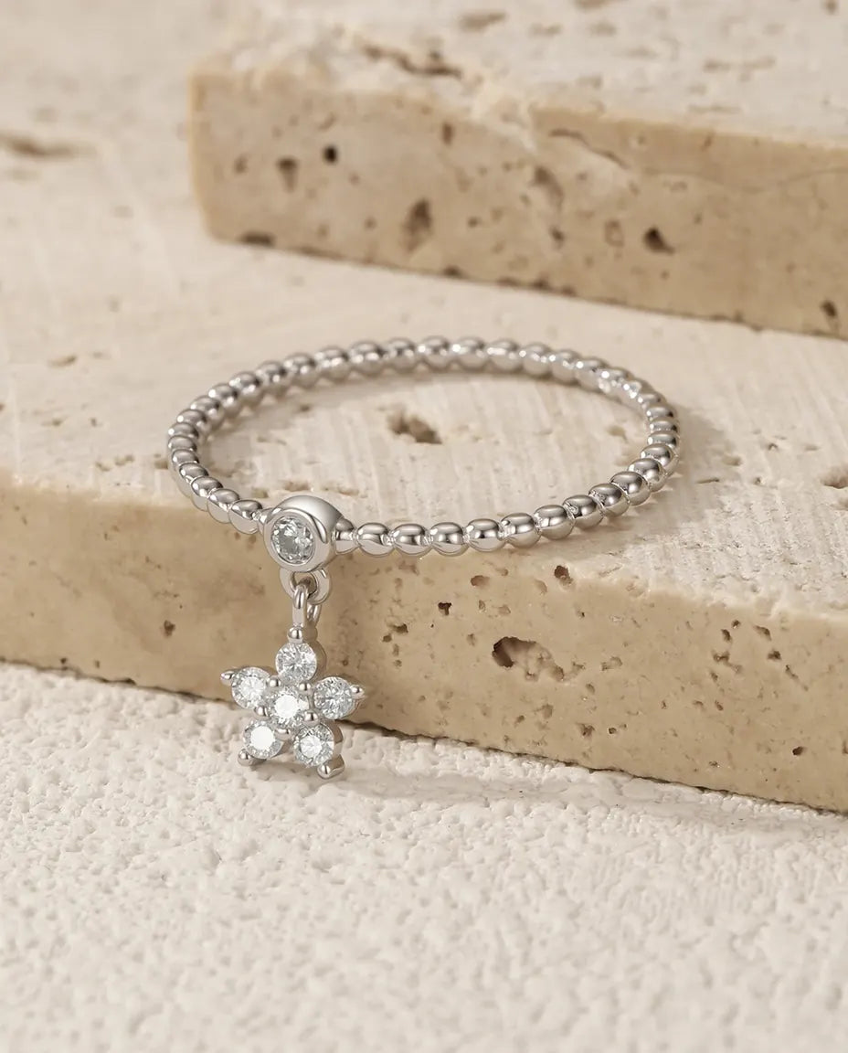Sølvring formet som en margerit med en lille dinglende moissanite under blomsten i 925 sterling sølv.